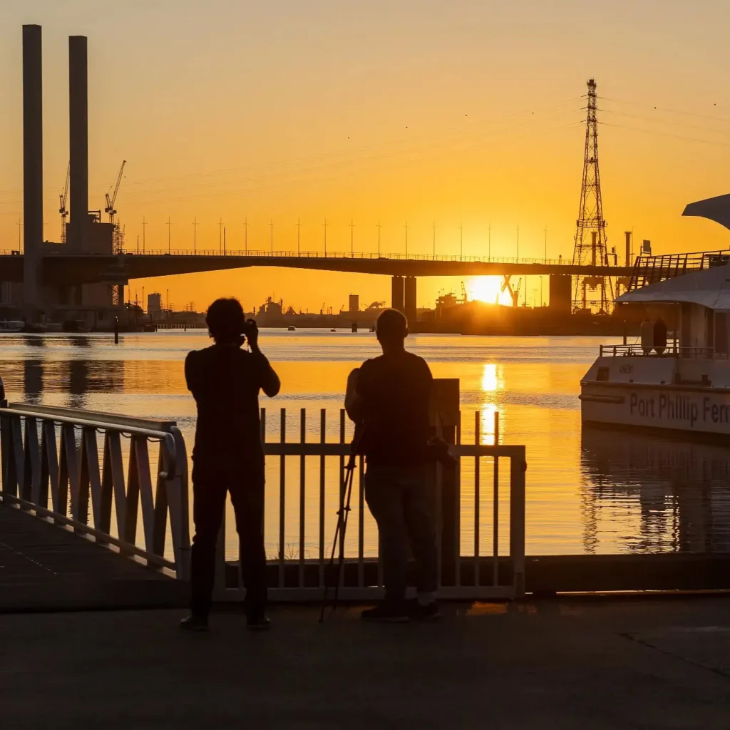 photographers in silhouette photographing the Bolte Bridge at sunset